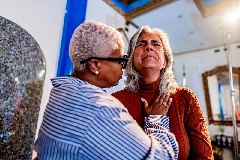A woman ministers to another woman who appears to be in distress